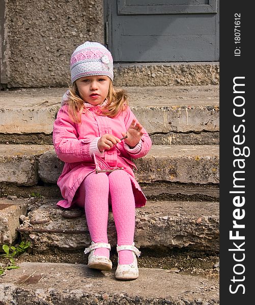 Little girl sits on a stone staircase
