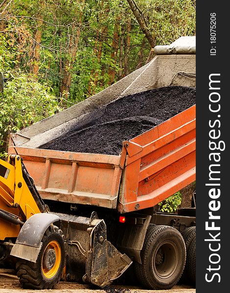 Process of unloading of asphalt of the lorry in a ladle of the building mechanism. Process of unloading of asphalt of the lorry in a ladle of the building mechanism