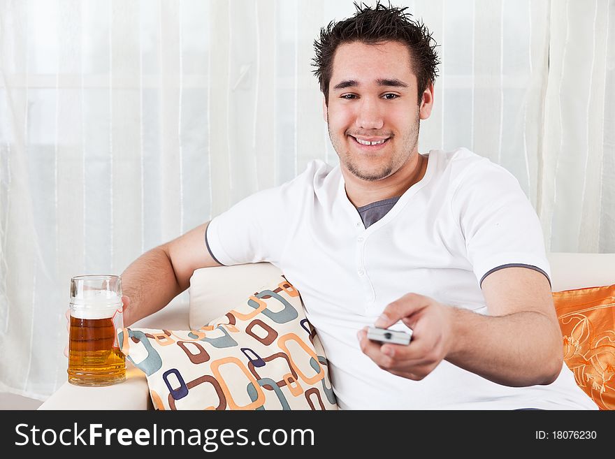 Young boy watching television and holding a glass of beer. Young boy watching television and holding a glass of beer