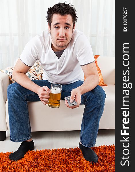 Young boy watching television and holding a glass of beer. Young boy watching television and holding a glass of beer
