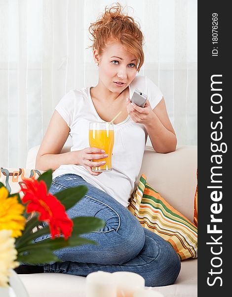 Beauty, young girl holding a glass of orange juice and a remote control. Beauty, young girl holding a glass of orange juice and a remote control