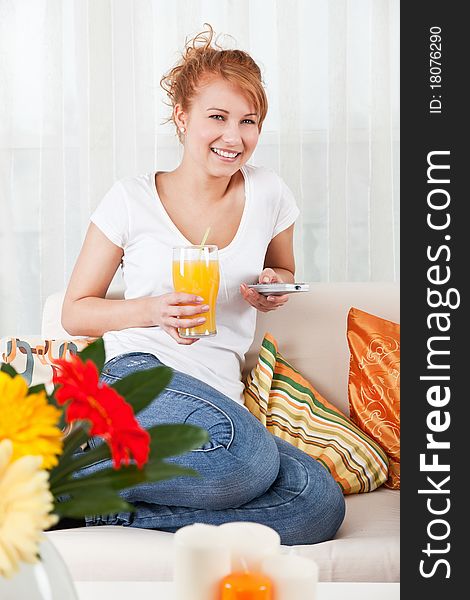 Beauty, young girl holding a glass of orange juice and a remote control. Beauty, young girl holding a glass of orange juice and a remote control