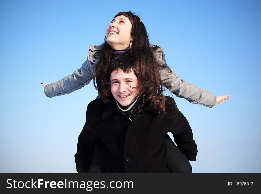 Happy young female enjoying a piggyback ride on boyfriends back with her hands outstretched. Happy young female enjoying a piggyback ride on boyfriends back with her hands outstretched