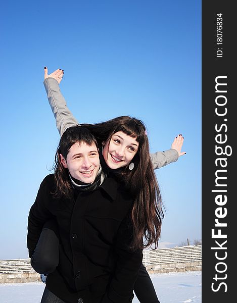 Happy young female enjoying a piggyback ride on boyfriends back with her hands outstretched. Happy young female enjoying a piggyback ride on boyfriends back with her hands outstretched