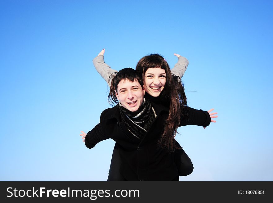 Happy young female enjoying a piggyback ride on boyfriends back with her hands outstretched. Happy young female enjoying a piggyback ride on boyfriends back with her hands outstretched