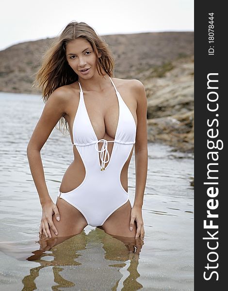 Young fashion brunette woman in swimwear on the beach. Young fashion brunette woman in swimwear on the beach