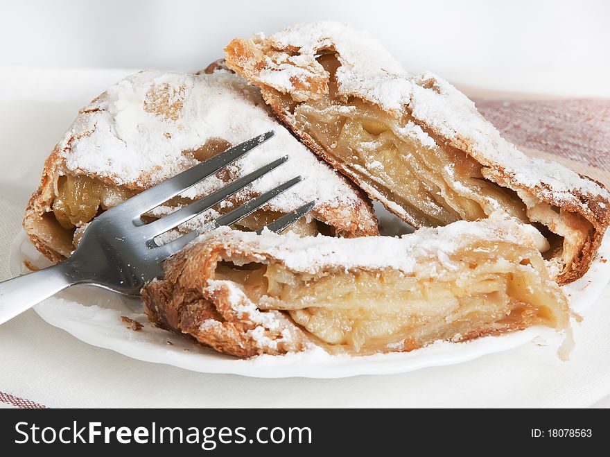 Piece apple strudel on a white plate on a light background. Piece apple strudel on a white plate on a light background