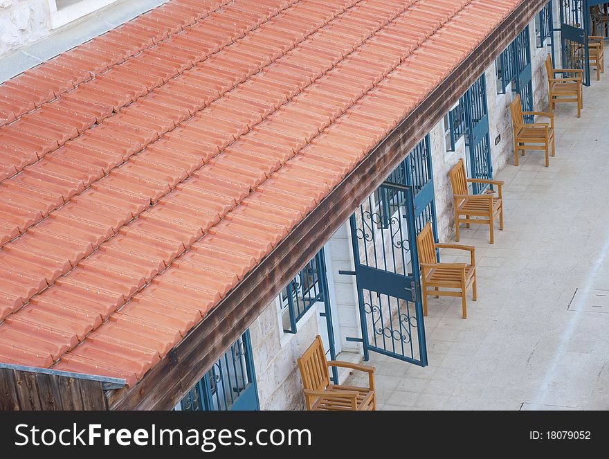 Courtyard with blue doors and wood chairs under red tile roof. Courtyard with blue doors and wood chairs under red tile roof