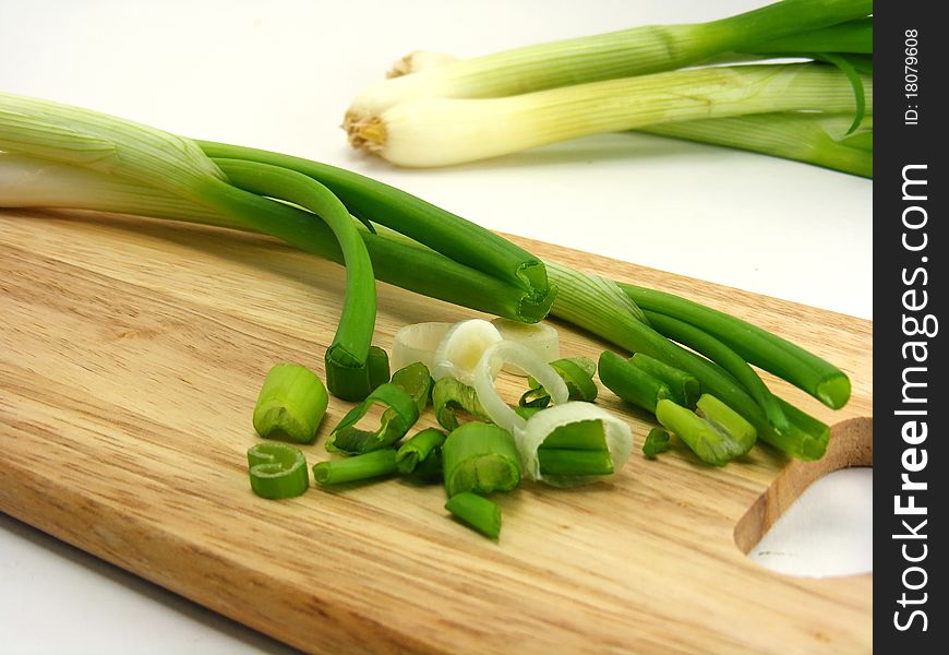 Chopped & whole spring onions on a wooden chopping board