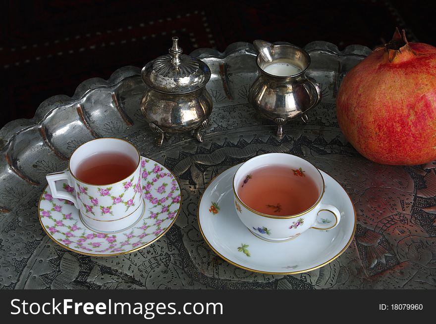 Oriental Tea Time Still Life with China Cups, Silverware and Grenadine Fruit Decoration