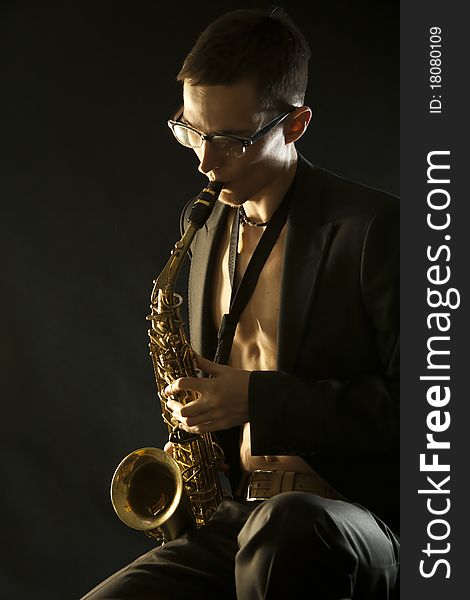 The young jazzman plaing a saxophone on black