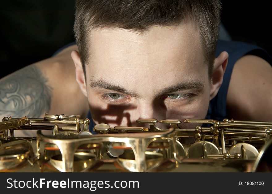 Closeup young jazz man look on saxophone. Closeup young jazz man look on saxophone