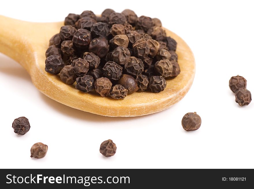 Black Peppercorns on a wooden spoon isolated