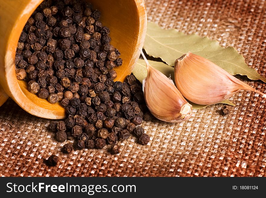 Black Peppercorns with garlic and a bay leaf still life