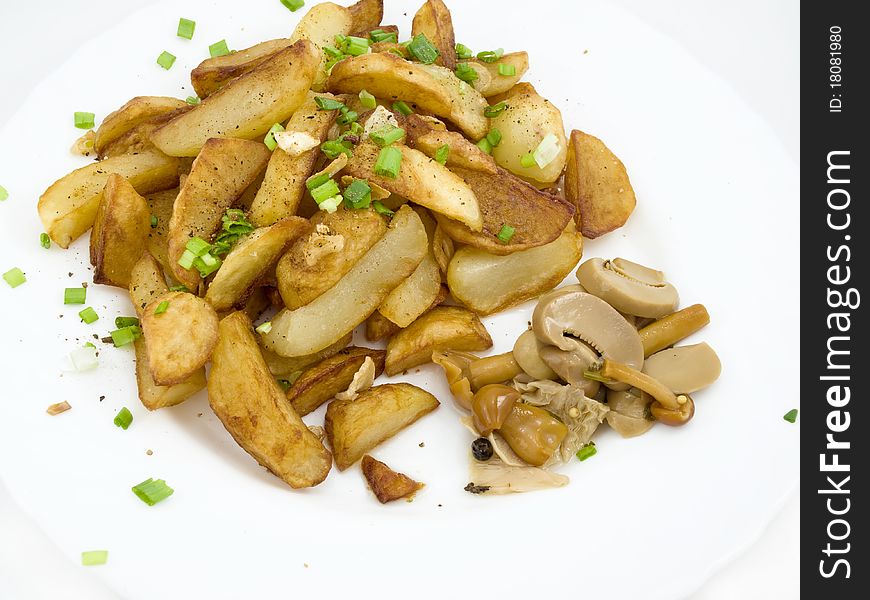 Fried potatoes with pickled mushroom on white plate and is sprinkled by verdure and spice