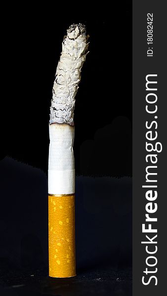 Lit standing cigarette isolated on black background