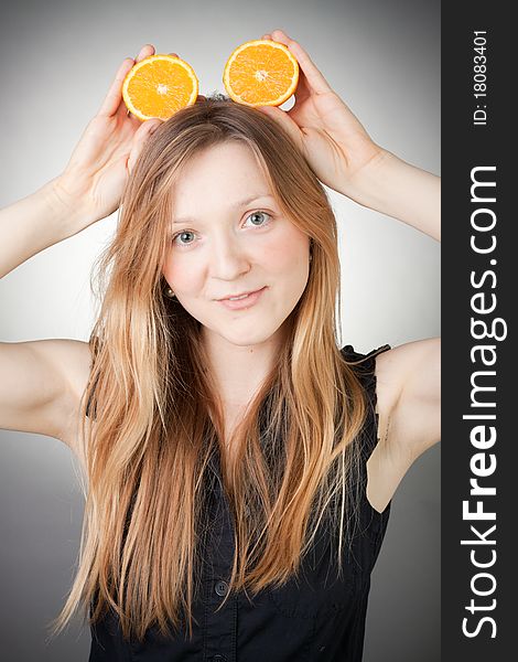 Beautiful woman holding two halfs of orange on her head like Mickey Mouse ears. Beautiful woman holding two halfs of orange on her head like Mickey Mouse ears