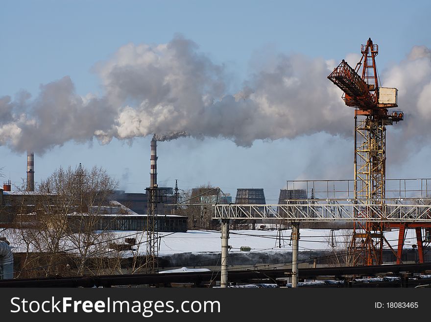 View of the smoking pipes and the industrial crane. View of the smoking pipes and the industrial crane