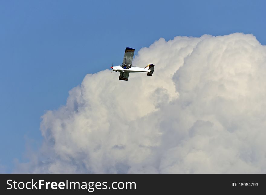 The easy passenger plane on a background of a beautiful cumulus cloud. The easy passenger plane on a background of a beautiful cumulus cloud