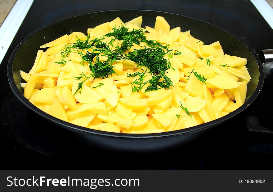 Sliced raw potatoes on frying pan in the kitchen