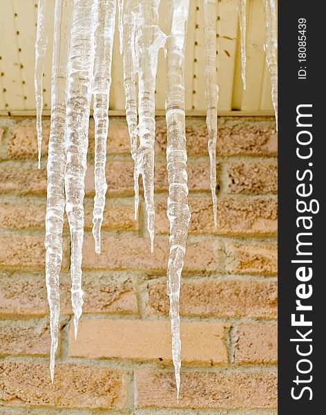 Bunch of icicles against a brick wall.