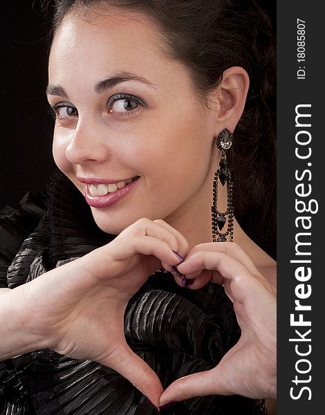 Girl posing to the camera and shows figure of a heart on fingers. Girl posing to the camera and shows figure of a heart on fingers