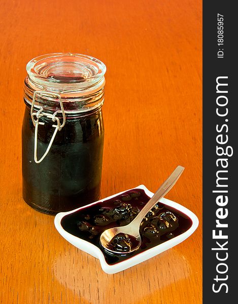 Glass jar and white bowl of blackberry jelly on old, wooden table. Glass jar and white bowl of blackberry jelly on old, wooden table