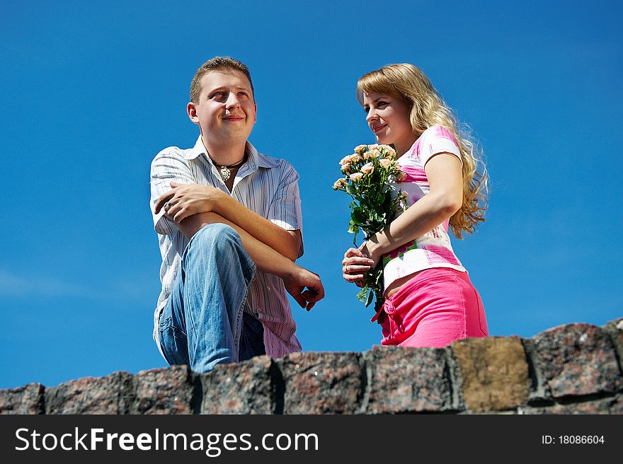 Young woman with flowers and her boyfriend on background blue sky
