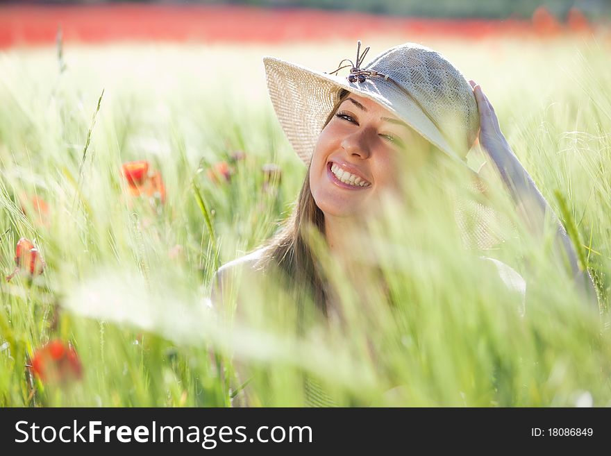 Young cheerful girl with hat staring at camera among green wheat. Young cheerful girl with hat staring at camera among green wheat.