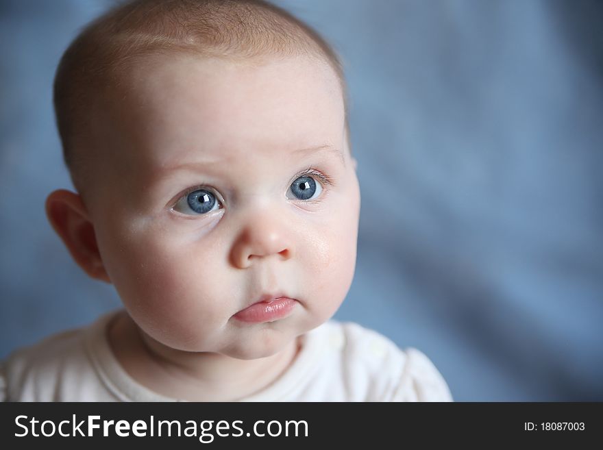 Portrait of adorable baby with big blue eyes on a blue background. Portrait of adorable baby with big blue eyes on a blue background