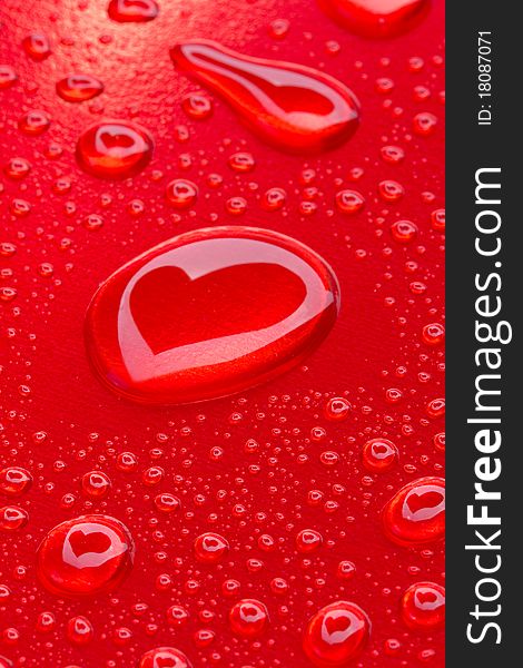 Heart reflected in drops on red background