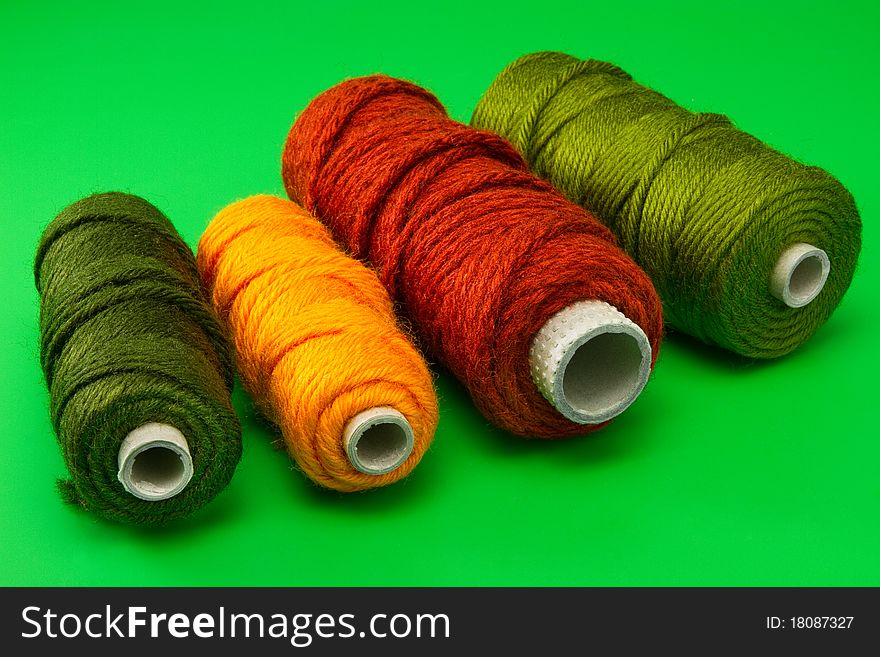 Bobbin with colorful threads in row on green background. Bobbin with colorful threads in row on green background
