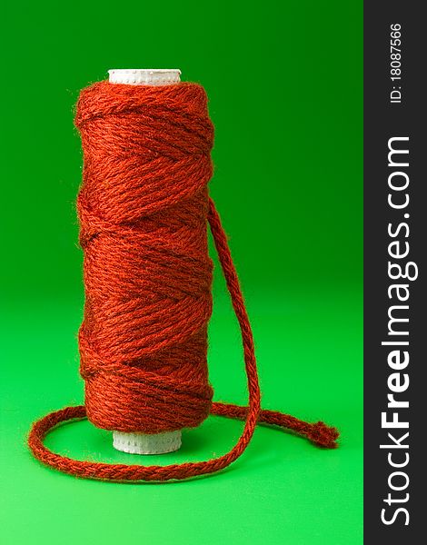 Bobbin of red thread on green background