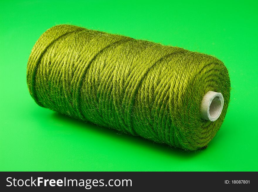 Bobbin of green thread on green background
