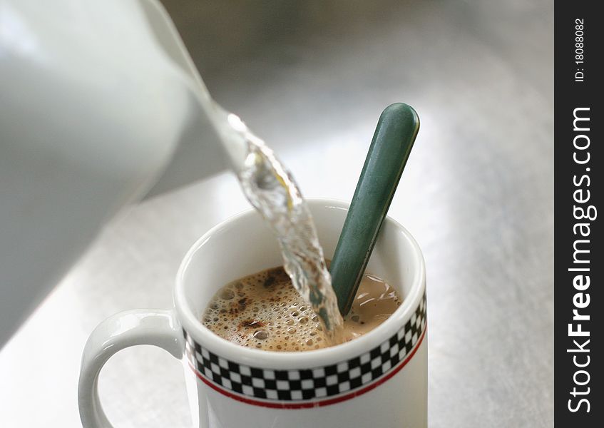 Pouring water into the morning cup of coffee. Pouring water into the morning cup of coffee