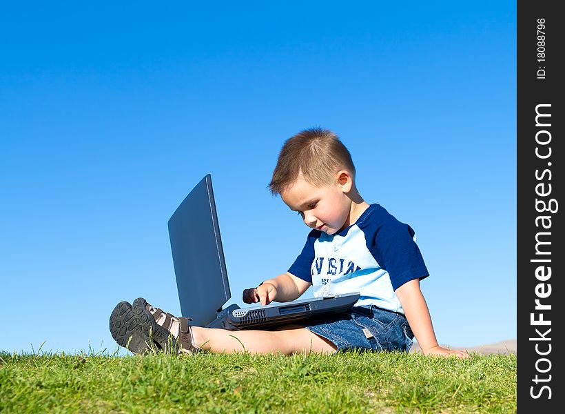 Little boy sitting down and playing with laptop. Little boy sitting down and playing with laptop