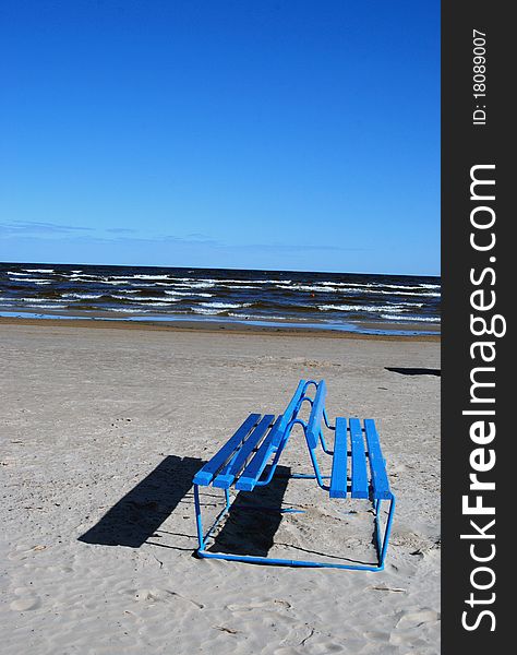 Blue empty bench near the sea in sunny day