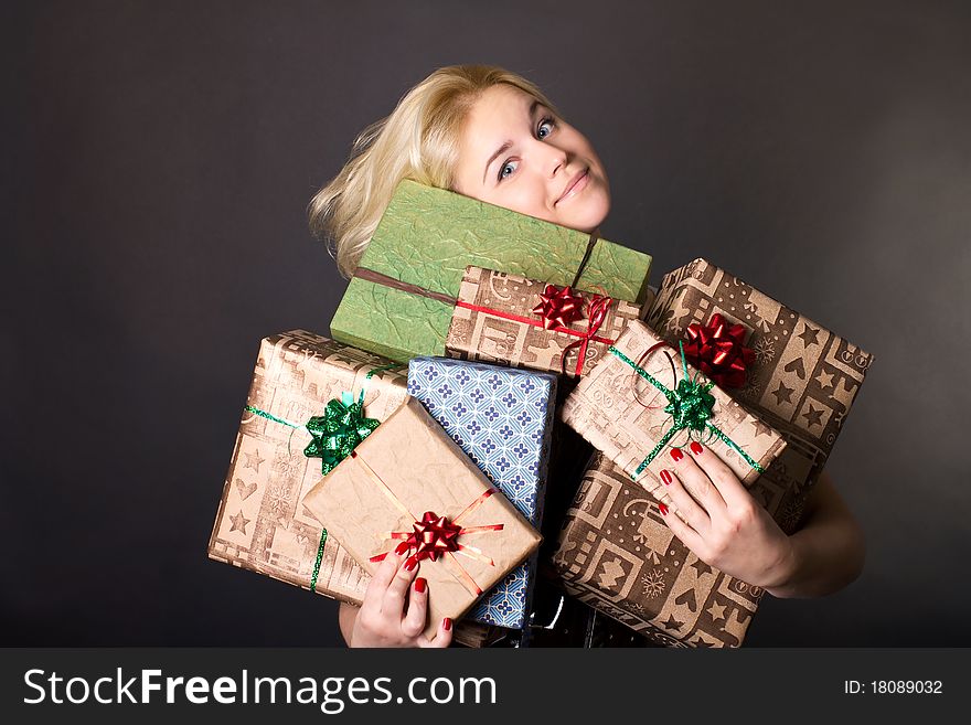 A lovely woman holding a many gift boxes on black background