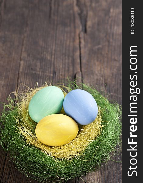 Colorful easter eggs in nest on wooden background
