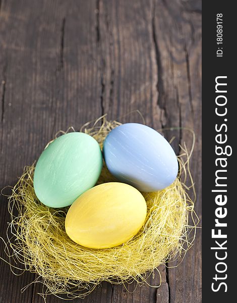 Colorful easter eggs in nest on wooden background