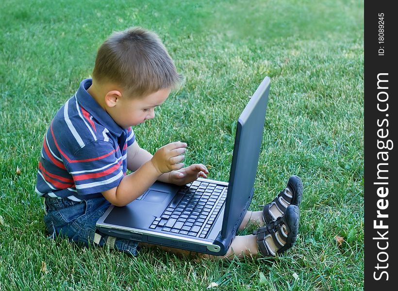 Little boy sitting down and playing with laptop. Little boy sitting down and playing with laptop