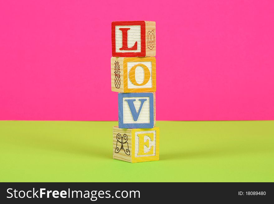 The word love spelled in childrens block with a pink and green background. The word love spelled in childrens block with a pink and green background.
