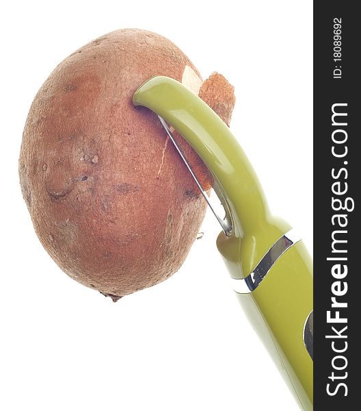 Sweet Potato Being Peeled with Green Vegetable Peeler.