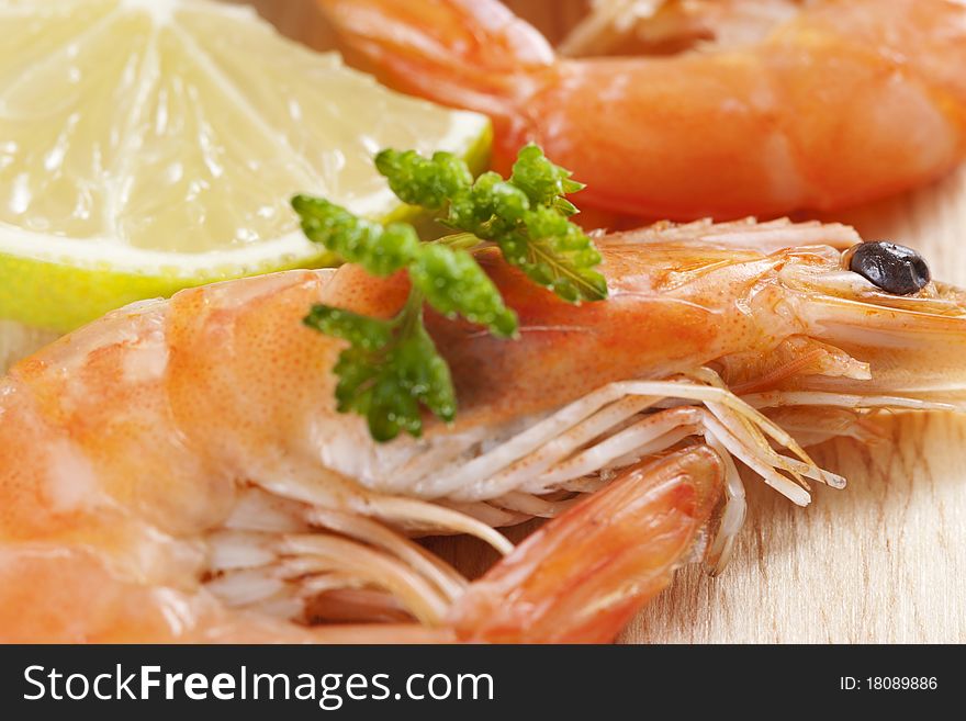 Shrimps on board with parsley and lemon wedges. Shrimps on board with parsley and lemon wedges