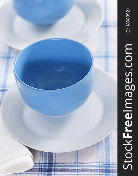 Two empty blue plates for the soup on a checkered tablecloth