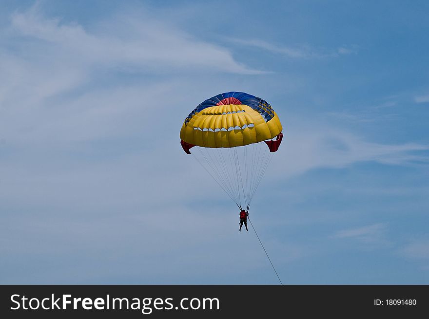 Paraglider launching from the ridge with colorful canopy against a blue sky. Paraglider launching from the ridge with colorful canopy against a blue sky.