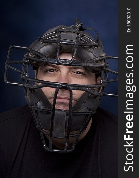 Thirty-something man in a catcher's mask with a dramatic blue background. Thirty-something man in a catcher's mask with a dramatic blue background.