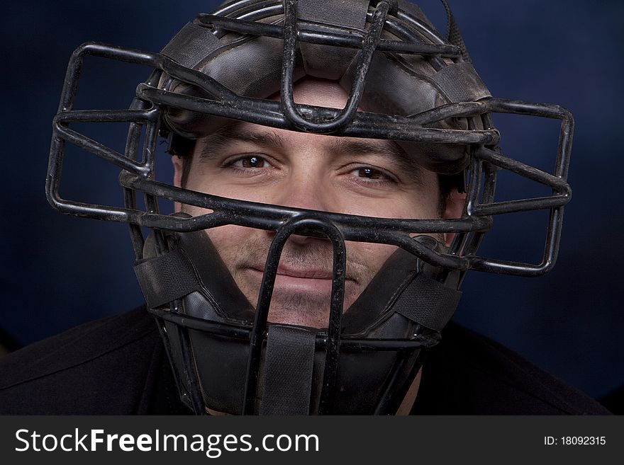 Thirty-something man in a catcher's mask with a dramatic blue background. Thirty-something man in a catcher's mask with a dramatic blue background.