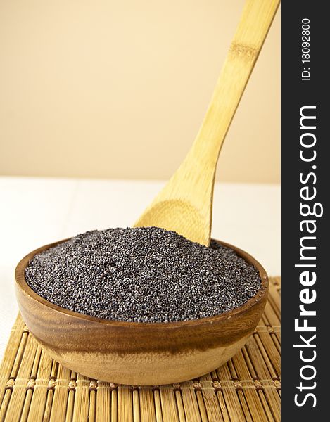 Poppy seeds in a wooden bowl on a table