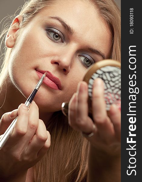 Pretty young woman applying make up. Pretty young woman applying make up.